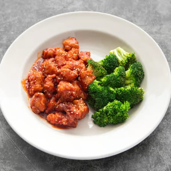 Mai Thai Restaurant's orange chicken with sesame seeds and a side of steamed broccoli on a white plate.