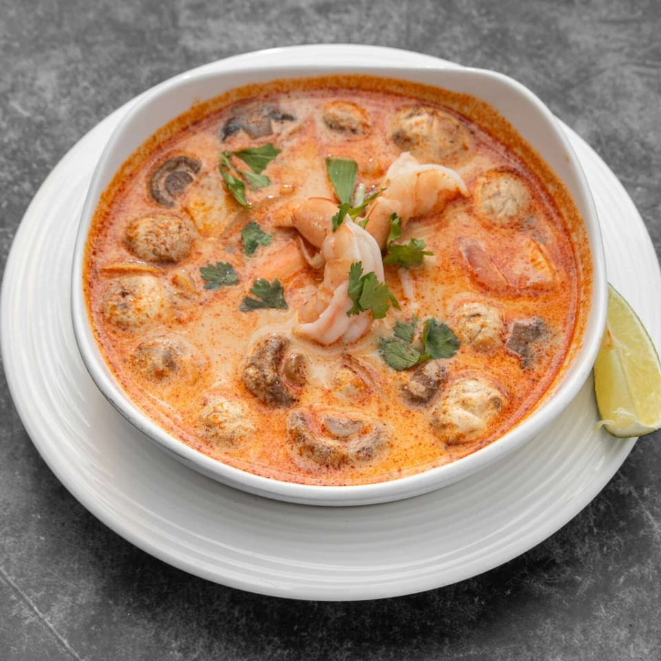 A bowl of Mai Thai Restaurant's Tom Yum soup with shrimp, mushrooms, and cilantro.